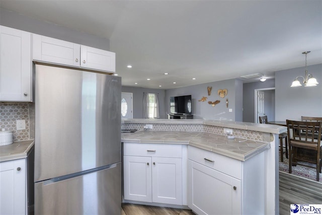 kitchen with decorative backsplash, white cabinetry, and freestanding refrigerator