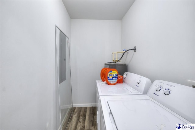 clothes washing area featuring baseboards, washing machine and dryer, water heater, laundry area, and wood finished floors