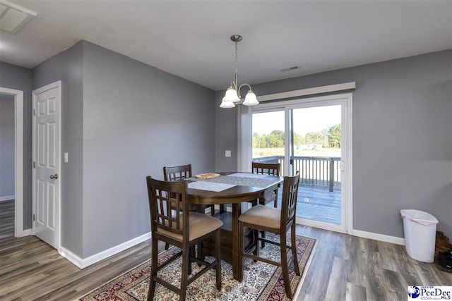 dining space featuring an inviting chandelier, wood finished floors, visible vents, and baseboards