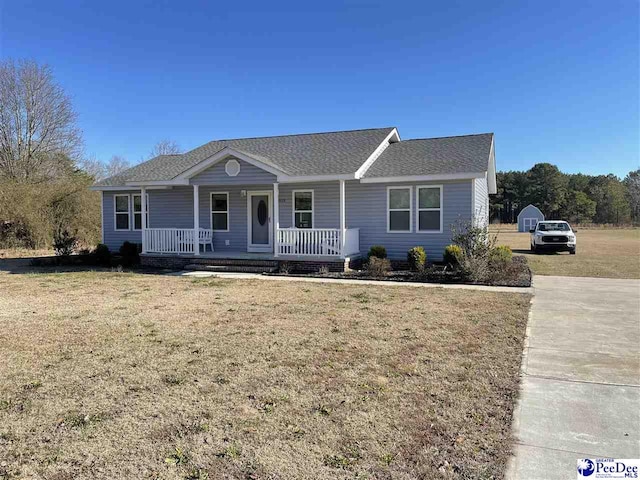 ranch-style house featuring roof with shingles, covered porch, and a front lawn