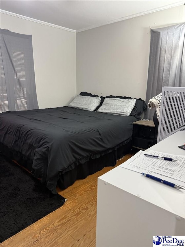 bedroom with ornamental molding and light hardwood / wood-style flooring