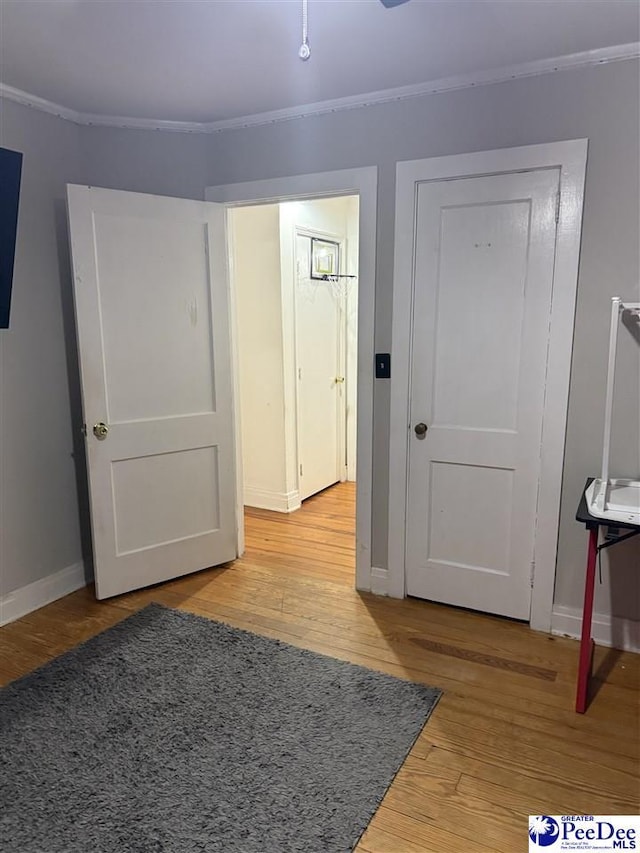 foyer entrance with crown molding, baseboards, and light wood-style floors