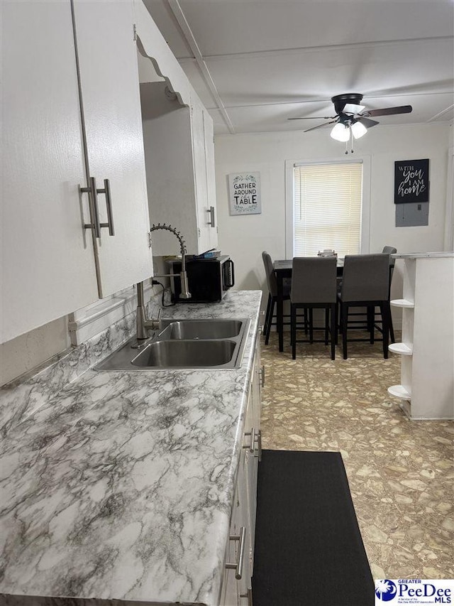 kitchen featuring white cabinetry, ceiling fan, and sink