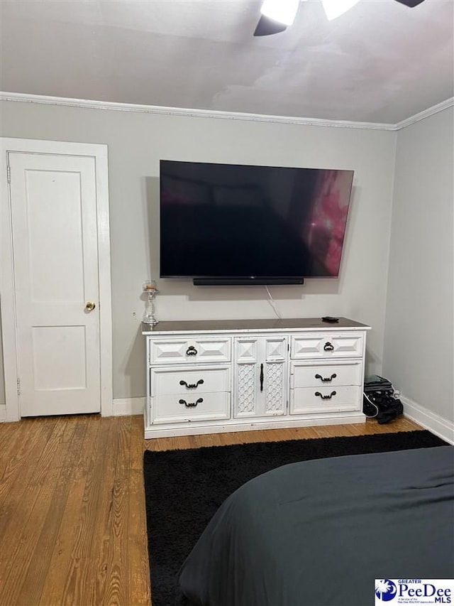bedroom with ornamental molding, ceiling fan, wood finished floors, and baseboards
