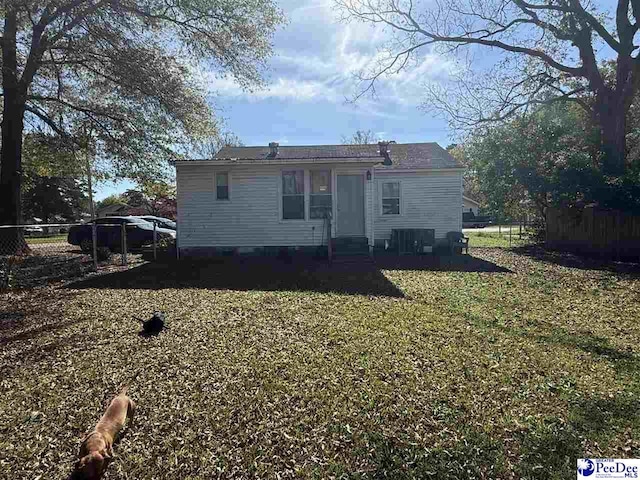 back of house featuring central AC unit and a yard