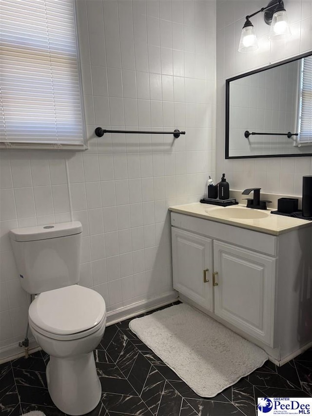 bathroom featuring tile walls, vanity, and toilet