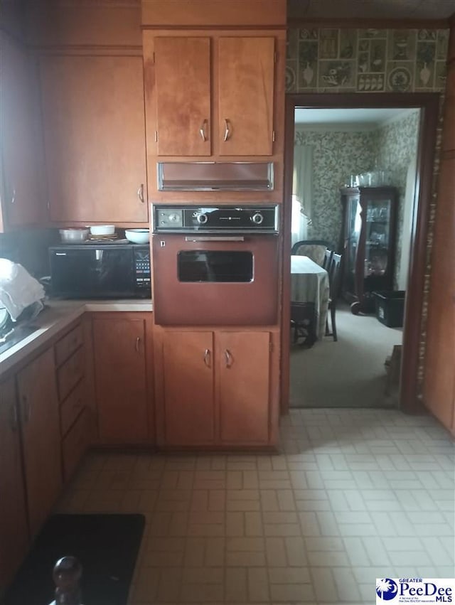 1815 Hampton Dr, Florence, SC 29505 - kitchen with wall oven, wallpapered walls, brown cabinetry, light countertops, and black microwave