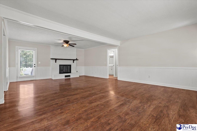 1526 Hunter St, Florence, SC 29505 - unfurnished living room featuring wainscoting, wood finished floors, a ceiling fan, a brick fireplace, and a textured ceiling
