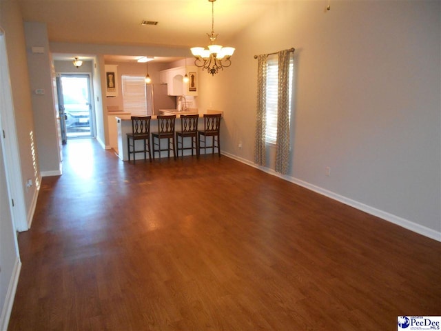 unfurnished dining area featuring dark wood-type flooring and an inviting chandelier