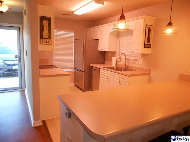 kitchen with white cabinetry, hanging light fixtures, sink, and appliances with stainless steel finishes