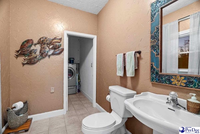 bathroom with toilet, sink, a textured ceiling, washer / clothes dryer, and tile patterned flooring