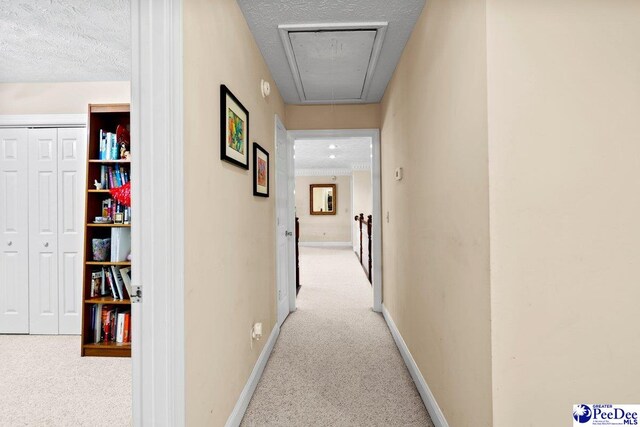 corridor with light colored carpet and a textured ceiling