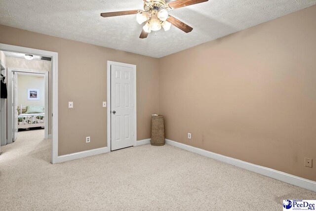 unfurnished bedroom with ceiling fan, carpet flooring, and a textured ceiling