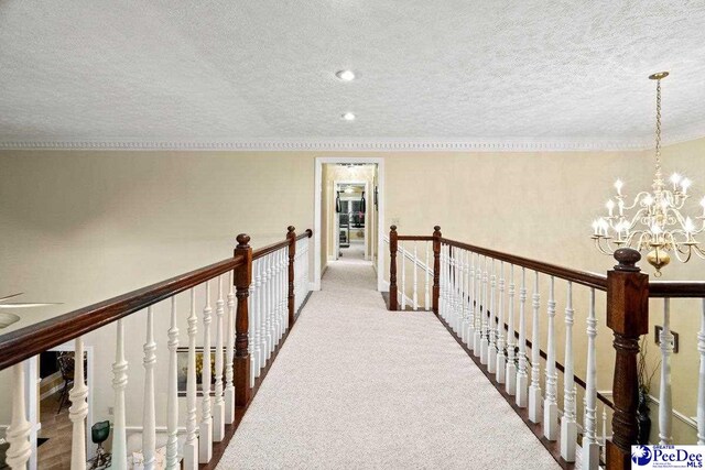 hallway with carpet floors, a textured ceiling, and an inviting chandelier