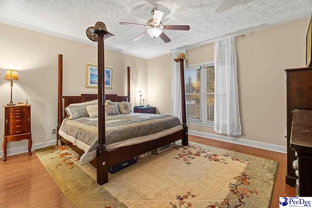 bedroom featuring ceiling fan, ornamental molding, a textured ceiling, and light wood-type flooring