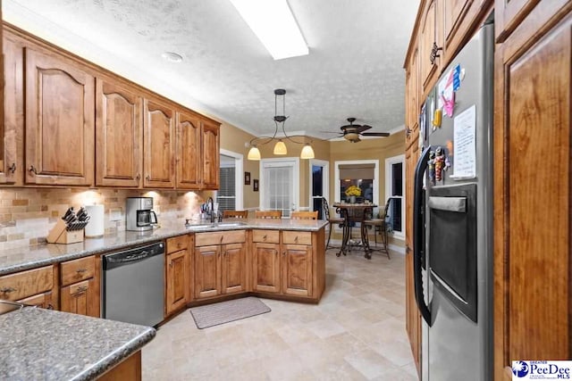 kitchen with pendant lighting, sink, appliances with stainless steel finishes, backsplash, and kitchen peninsula