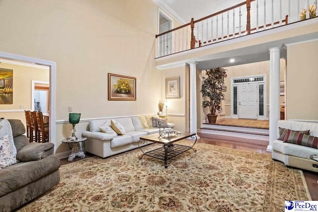 living room featuring decorative columns, wood-type flooring, and a high ceiling