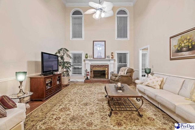 living room featuring crown molding, a brick fireplace, and ceiling fan