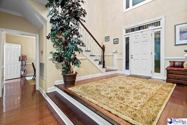 foyer with dark wood-type flooring and a towering ceiling