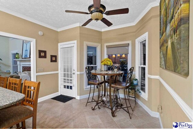 dining space with ceiling fan, ornamental molding, and a textured ceiling