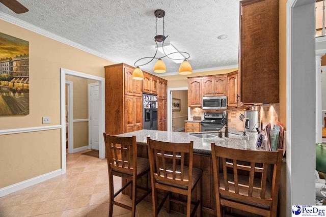 kitchen featuring sink, a breakfast bar area, hanging light fixtures, stainless steel appliances, and kitchen peninsula