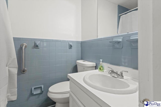 bathroom featuring wainscoting, toilet, a shower with shower curtain, vanity, and tile walls