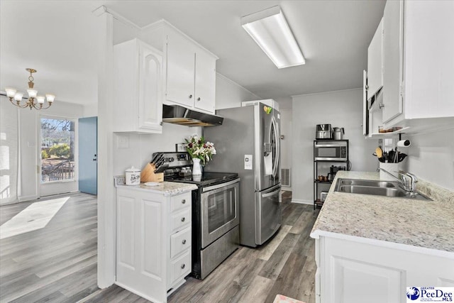 kitchen featuring white cabinets, appliances with stainless steel finishes, wood finished floors, under cabinet range hood, and a sink