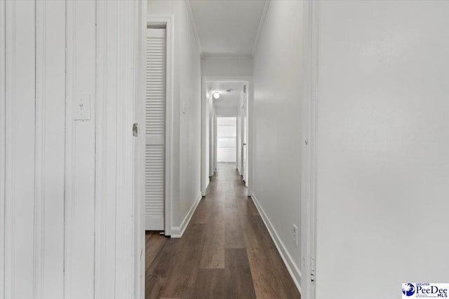 corridor featuring ornamental molding, dark wood-type flooring, and baseboards