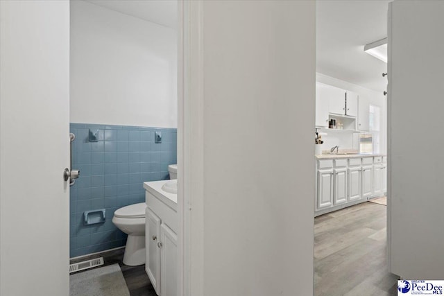 bathroom featuring tile walls, visible vents, vanity, and toilet