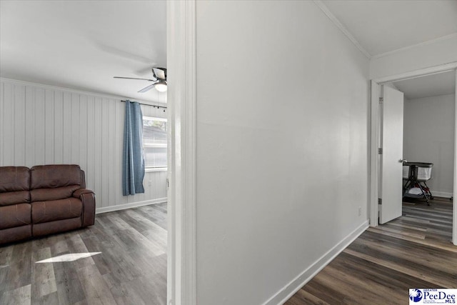 hallway featuring baseboards, ornamental molding, and wood finished floors