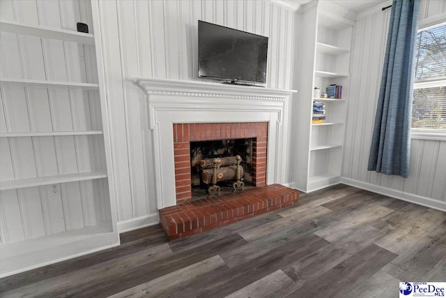 unfurnished living room with baseboards, a fireplace, wood finished floors, and built in features