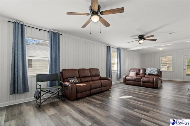 living area featuring wood finished floors, a ceiling fan, and baseboards