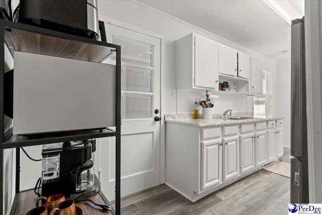 kitchen featuring light wood-type flooring, open shelves, white cabinets, and a sink