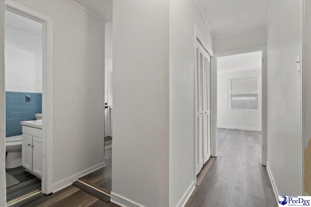 hall with dark wood-style floors, ornamental molding, and baseboards