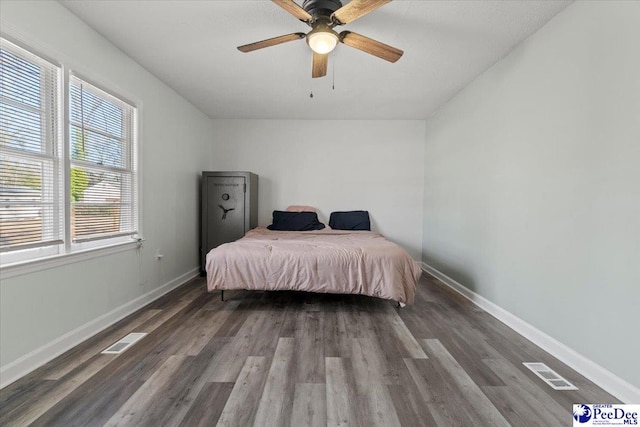 bedroom with a ceiling fan, baseboards, visible vents, and wood finished floors