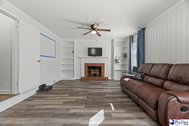 living area featuring built in shelves, ornamental molding, and wood finished floors