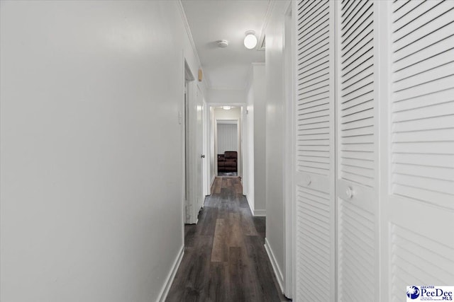 corridor featuring dark wood-style floors, crown molding, and baseboards