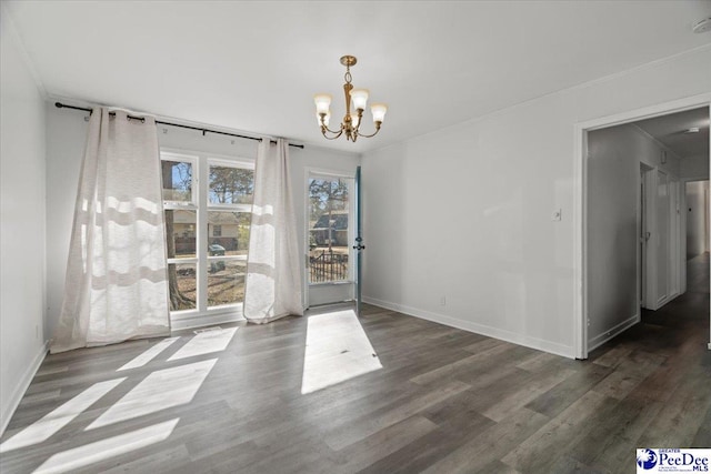 unfurnished dining area with baseboards, crown molding, dark wood finished floors, and an inviting chandelier