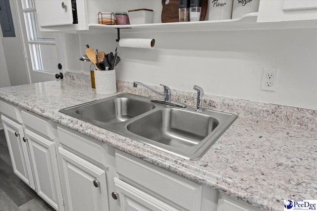 kitchen with white cabinets, a sink, and light stone countertops