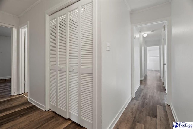 hallway with ornamental molding, dark wood-type flooring, and baseboards