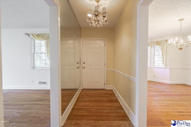 entryway featuring a textured ceiling, wood-type flooring, and a chandelier