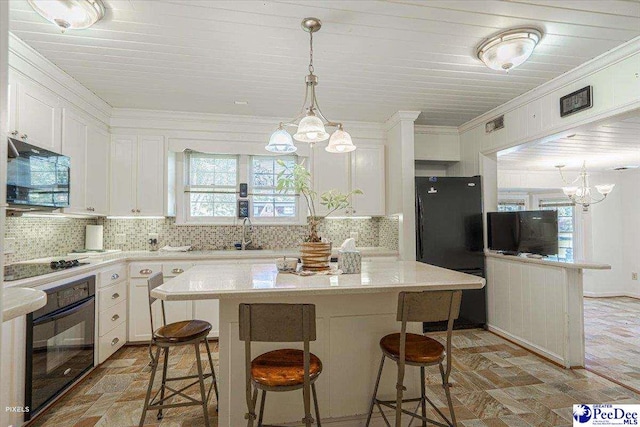 kitchen with white cabinetry, a center island, a chandelier, and black appliances