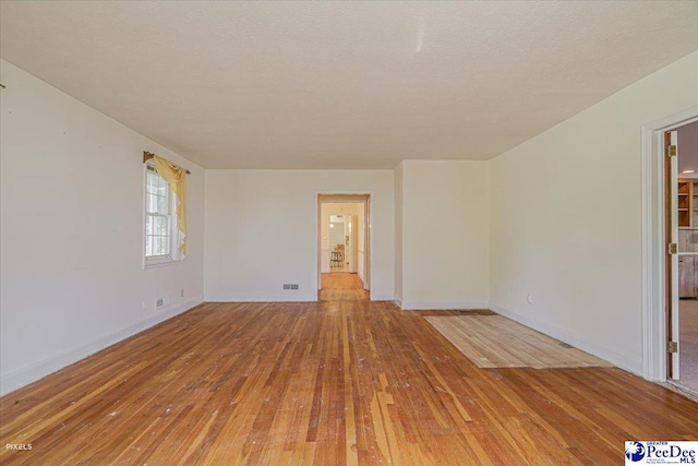 unfurnished room featuring wood-type flooring and a textured ceiling