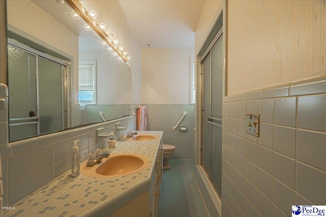 bathroom featuring vanity, a shower with shower door, tile walls, and toilet