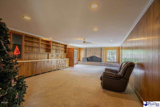 living room with wooden walls, light colored carpet, ornamental molding, and a fireplace