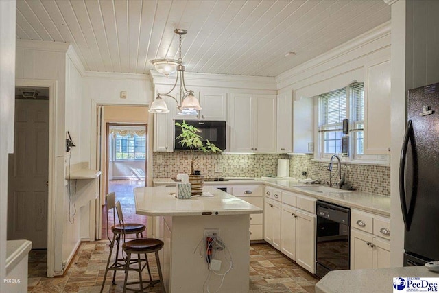 kitchen with pendant lighting, sink, a center island, tasteful backsplash, and black appliances