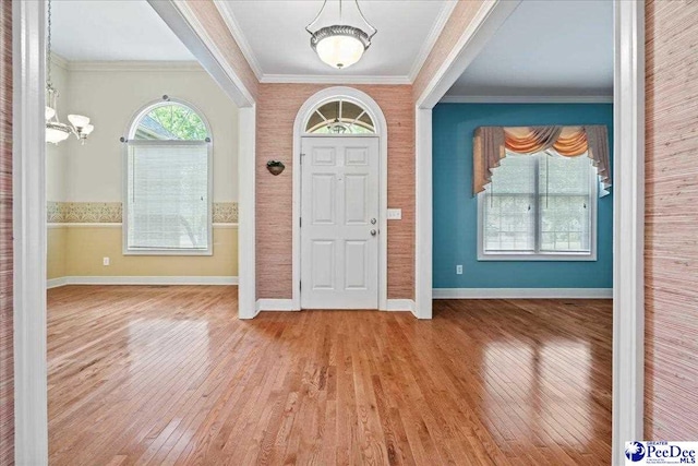 foyer entrance with crown molding, baseboards, and wood finished floors