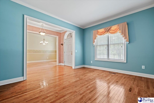 empty room featuring wood finished floors, ornamental molding, visible vents, an inviting chandelier, and baseboards