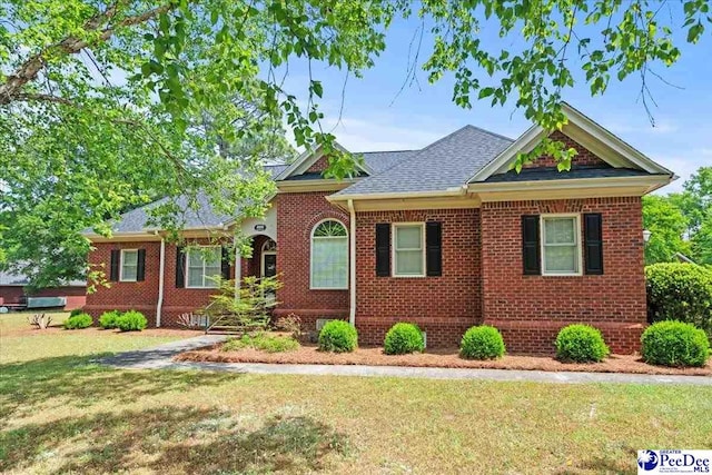 ranch-style house featuring a front lawn, a shingled roof, and brick siding