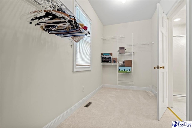 walk in closet with light colored carpet and visible vents